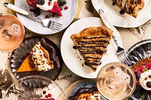 An assortment of pie slices served on plates topped with fruit or drizzled with sauces