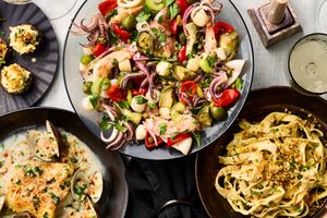 A display of seafood dishes served on a table including pasta salad and clams