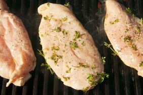 Chicken breasts marinating with herbs and spices on a grill