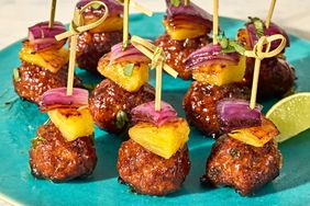 Meatballs served with skewered pineapple and red onion on a plate