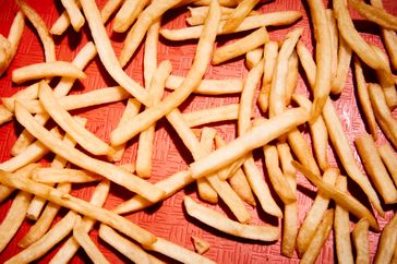 A closeup of French fries spread across a red surface