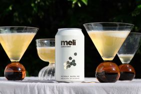 A can of Meli quinoa beer surrounded by cocktails in stemmed glassware