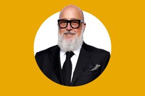 Andrew Zimmern smiling in a suit and tie