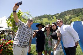 A group of people outdoors smiling for a selfie standing in a scenic mountain area with a large decor element behind them