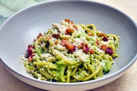 A bowl of pasta topped with diced bacon and grated cheese