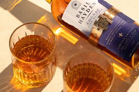 Bottle of Basil Hayden Cognac Cask Reserve with two filled glasses on a surface