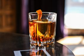 A glass of an Old Fashioned cocktail garnished with citrus peel