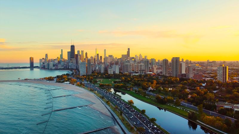Chicago Skyline and Lake Michigan at Sunset. Aerial view of Chicago's skyline along Lake Michigan at sunset, with beaches, parks, and a busy lakeside road framed by warm evening light
