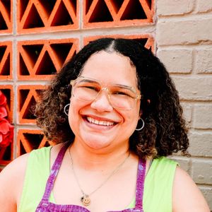 Person smiling in front of a brick wall with a patterned section
