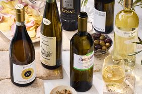 Assorted bottles of Vermentino wine with a glass served olives and snacks