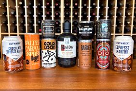 Variety of canned espresso martinis and cocktail beverages displayed on a wooden surface with a wine rack background