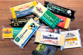 A variety of sharp cheddar cheese packages arranged on a wooden surface
