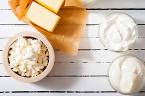 A selection of dairy products including butter cottage cheese and creams arranged on a white wooden surface