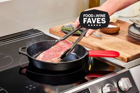 setting raw steak on hot cast iron with tongs