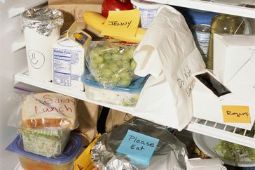 Several labeled food items and containers are arranged inside a refrigerator