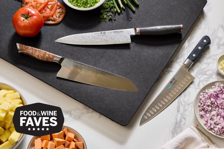 Chef Knives being placed on a black cutting board with food displayed around