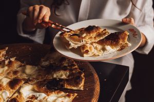 Person serving slices of cheesestuffed focaccia onto a plate