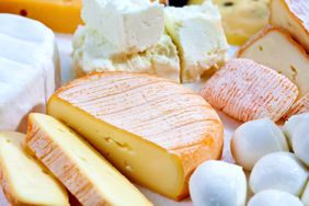 Variety of cheeses arranged including sliced and whole pieces of different types