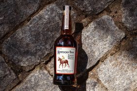 A bottle of Kentucky Boy Straight Bourbon Whiskey placed on a cobblestone surface