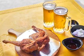 Fried chicken with dipping sauces next to mugs of beer on a table