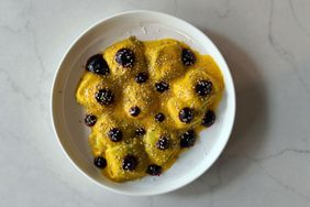 Plate of ravioli with sauce and garnishes served on a marble surface