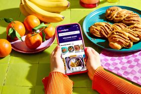 Person viewing a recipe app on a smartphone at a table with fruit and pastries