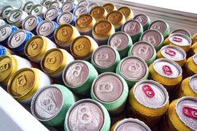 Various cans of beverages in rows, some covered with condensation, arranged in a cooler or fridge