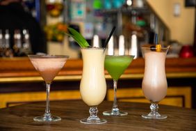 A selection of four different cocktails served in various glassware on a bar counter
