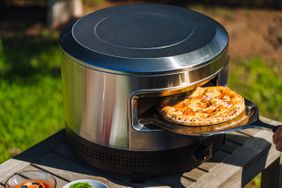 A round pizza retrieved from a Solo Stove Pi Prime Pizza Oven outside.