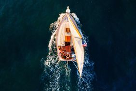 A topdown view of a sailboat on the water with people on deck