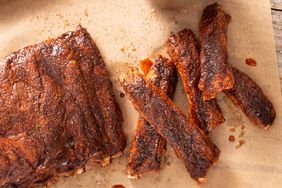 Barbecued ribs on parchment paper showing a full rack and several individual ribs