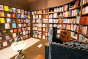 A cozy bookstore with shelves of books a vintage cash register in the foreground displaying a No Sale sign