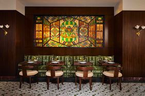 Dining area with a stained glass decoration on the wall above seating and tables