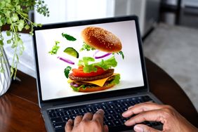 A person using a laptop displaying a virtual hamburger creation in progress