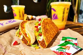 Taco Bell food items including tacos drinks and condiments on a table