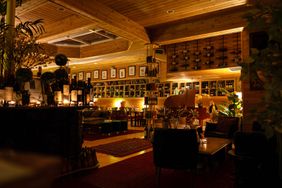 Interior of a wine bar with wooden decor shelves with bottles cozy seating areas and warm lighting