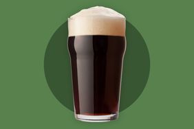 A stout in a pint glass over a green background.