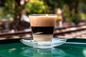 A glass cup with egg coffee on top of a green table on the train street in Hanoi, Vietnam.