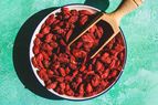 A bowl of dried goji berries with a wooden scoop