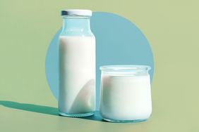 A glass bottle and cup with milk over a blue and green background.